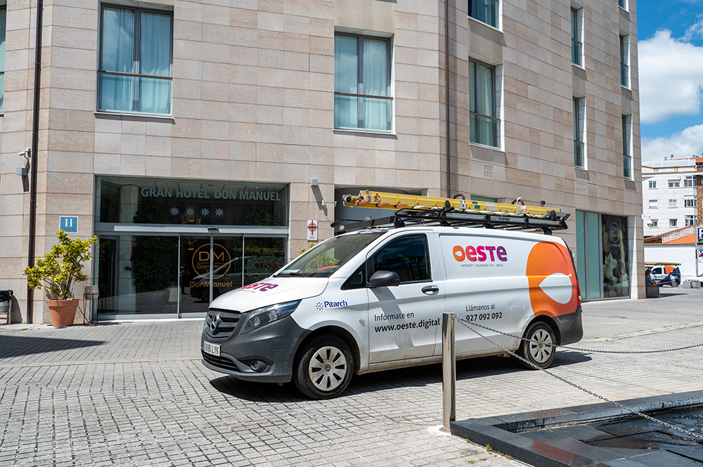 Vehículo técnico de OESTE Digital estacionado frente al Gran Hotel Don Manuel para la instalación y mantenimiento de servicios de fibra óptica y telecomunicaciones.
